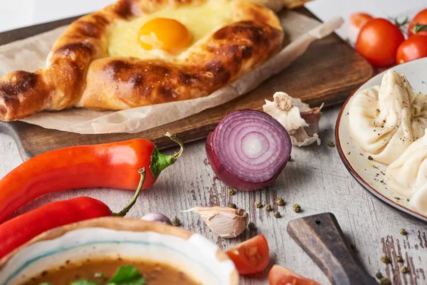 Adjarian khachapuri, soup kharcho and khinkali with spices and vegetables on table — Stock Image Adjarian Khachapuri Soup Kharcho Khinkali Spices Vegetables Table Stock Photo