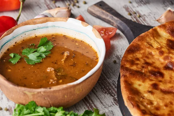 Imereti khachapuri and soup kharcho with spices, cilantro and vegetables on table — Stock Image Imereti Khachapuri Soup Kharcho Spices Cilantro Vegetables Table Stock Photo