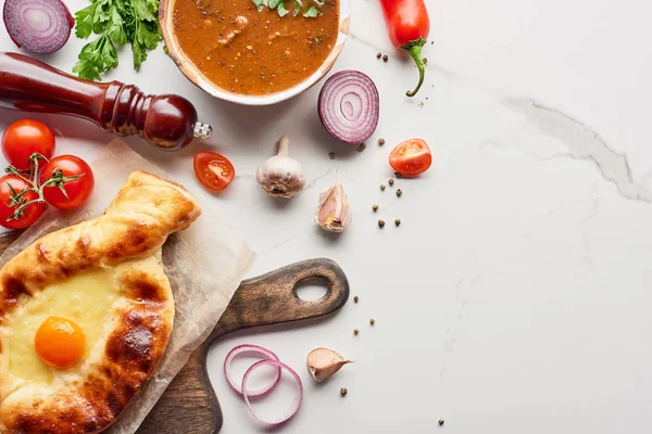 Top view of adjarian khachapuri, soup kharcho, vegetables and spices on marble texture — Stock Image Top View Adjarian Khachapuri Soup Kharcho Vegetables Spices Marble Texture Stock Photo
