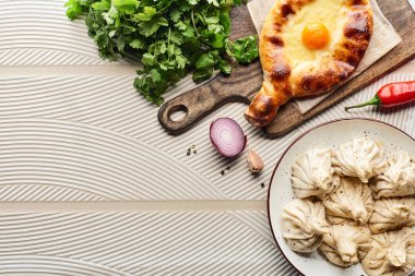 Sebze ve baharatların yanında bej desenli arka planda lezzetli khinkali ve adjarian khachapuri manzarası