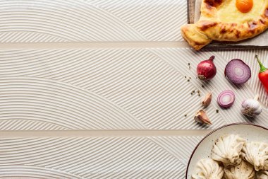 Sebze ve baharatların yanında bej desenli arka planda lezzetli khinkali ve adjarian khachapuri manzarası