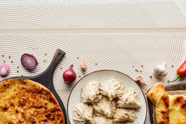 Sebze ve baharatların yanında bej desenli arka planda lezzetli khinkali ve khachapuri manzarası