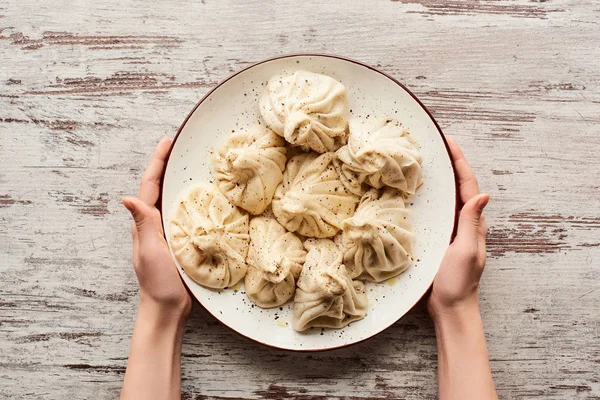 Vista Recortada Mujer Sosteniendo Plato Con Delicioso Khinkali Mesa Madera — Foto de Stock