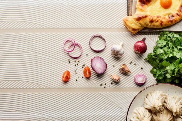 在米色纹理背景的蔬菜和调味品附近 可以俯瞰美味的Khinkali和Adjarian Khachapuri — 图库照片