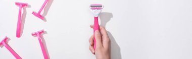 cropped view of woman holding female pink razor on white background, panoramic shot clipart