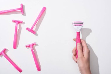 cropped view of woman holding female pink razor on white background clipart