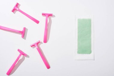 Beyaz arka planda kadın pembe jiletleri ve tüy dökücü şeritlerin üst görüntüsü