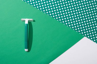 Yeşil noktalı arkaplanda yeşil tek kullanımlık jiletin üst görünümü