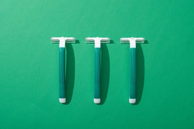 flat lay with green disposable razors on green background clipart