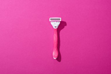 Pembe arka planda kadın traş makinesinin üst görüntüsü