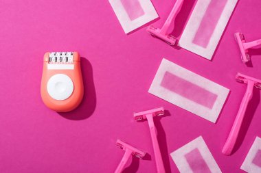 Pembe arka planda tek kullanımlık ustura, epilatör ve balmumu tüy dökücü çizgilerin üst görünümü