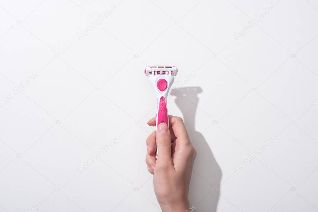 cropped view of woman holding female pink razor on white background