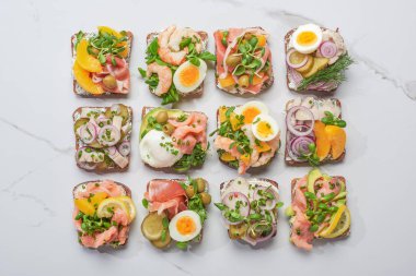 Beyaz mermer yüzeyde geleneksel Danimarka usulü smorrebrod sandviçlerin üst görüntüsü 