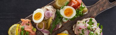 panoramic shot of wooden cutting board with fresh danish smorrebrod sandwiches on grey surface  clipart