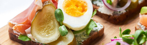 panoramic shot of ham, pickled cucumber and half of boiled egg on danish smorrebrod 