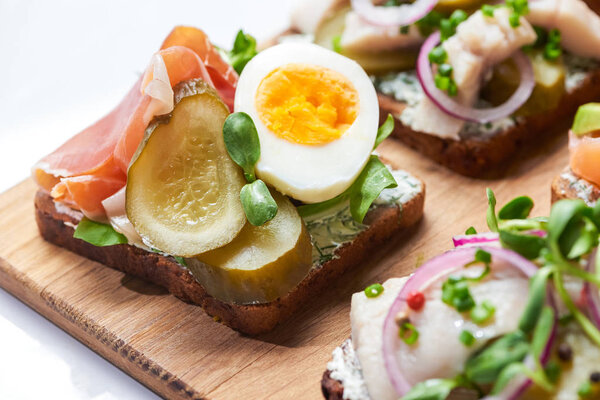 selective focus of ham, pickled cucumber and half of boiled egg on danish smorrebrod on white