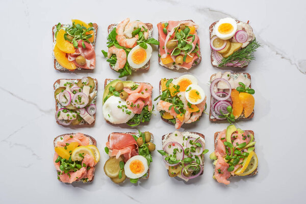 top view of traditional danish smorrebrod sandwiches on white marble surface 