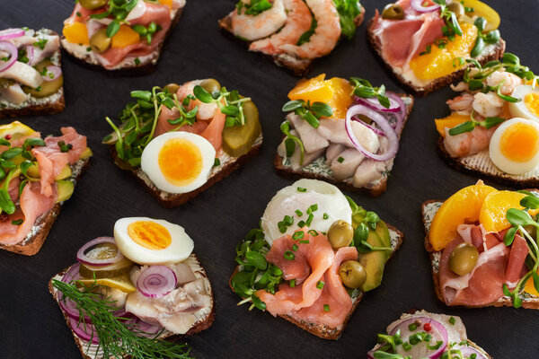 selective focus of rye bread with prepared danish smorrebrod sandwiches on grey surface 