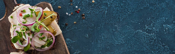 panoramic shot of rye bread with smorrebrod sandwich near peppercorns on blue surface 