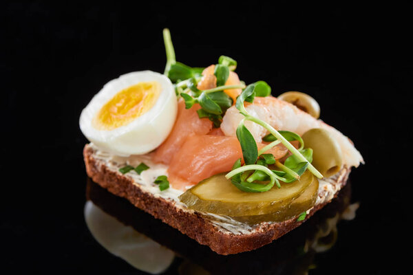 close up of boiled egg near fresh salmon on danish smorrebrod sandwich on black 