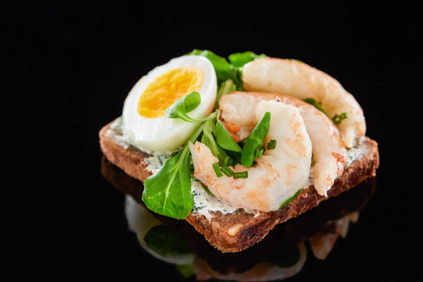 close up of boiled egg near shrimps on delicious danish smorrebrod sandwich on black 