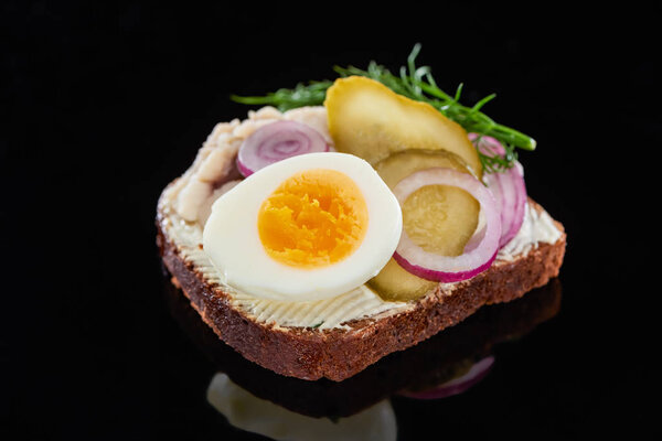 close up of boiled egg on delicious danish smorrebrod sandwich on black 