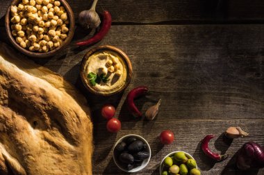 Lezzetli humus, nohut, pide, baharat ve zeytin ağaçtan yapılmış sade masa manzarası.