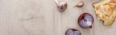 top view of delicious fresh baked pita, garlic and red onion on beige wooden table, panoramic shot clipart