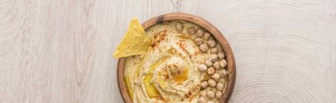 Bej ahşap masada nohut ve nacho ile nefis humus manzarası, panoramik çekim.