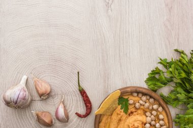 Lezzetli humus, nohut, baharatların yanında nacho ve bej ahşap masada maydanoz.