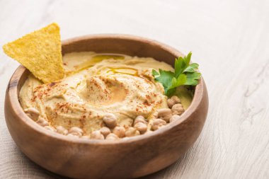 Bej ahşap masada nohut ve nacho ile nefis humus manzarasını kapatın.
