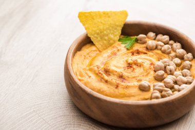 Bej ahşap masada nohut ve nacho ile nefis humus manzarasını kapatın.