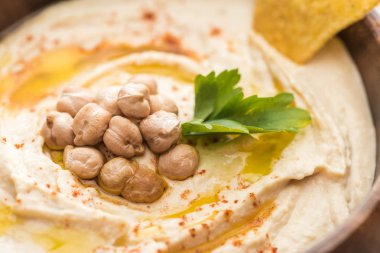 close up view of delicious hummus with chickpeas and nacho in bowl clipart