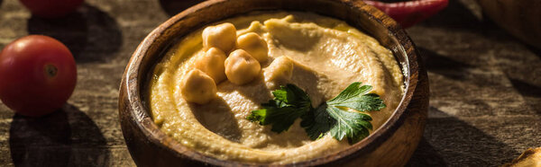 delicious hummus, chickpeas, cherry tomatoes on wooden rustic table, panoramic shot