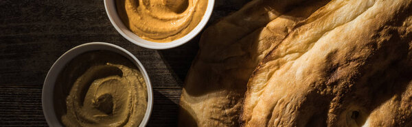 top view of delicious assorted hummus near fresh baked pita on wooden rustic table, panoramic shot
