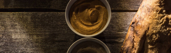 top view of delicious assorted hummus and fresh baked pita on wooden rustic table, panoramic shot