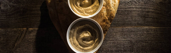 top view of delicious assorted hummus on fresh baked pita on wooden rustic table, panoramic shot