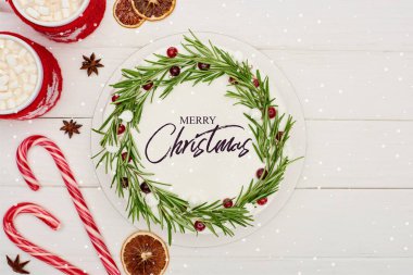 Çubuk şeker, iki fincan kakao ve Noel pastası. Beyaz ahşap masada Mutlu Noeller illüstrasyonu. 