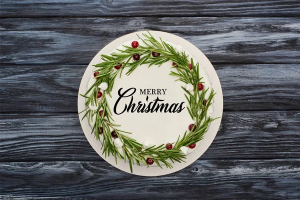 用白色糖霜 迷迭香和蔓越橘装饰的传统圣诞派的顶部视图 用快乐的圣诞插图装饰着深色木制桌子 — 图库照片