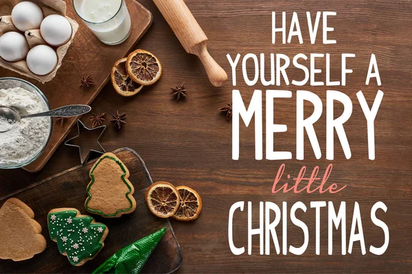 在木制桌子上靠近配料和调味品的美味圣诞饼干的顶部 有一个愉快的圣诞小插画 — 图库照片