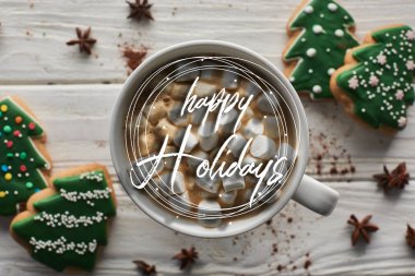 Noel kakaosunun en üst görüntüsü, beyaz ahşap masa üzerinde şekerleme ve mutlu bayramlar resimli kurabiyeler. 