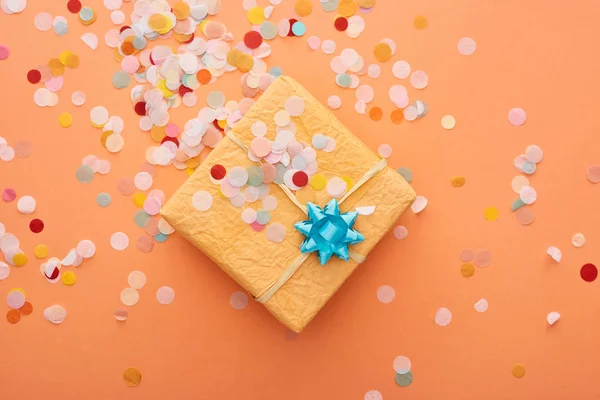 Bovenaanzicht Van Geschenkdoos Met Blauwe Strik Bij Confetti Oranje — Stockfoto