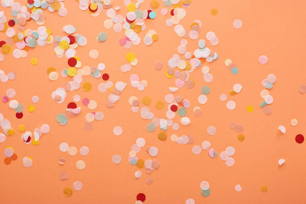 decorative and colorful confetti on orange background 