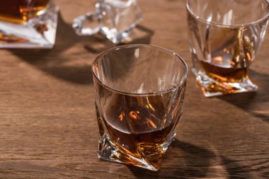 Selective focus of brandy in glasses on wooden table clipart