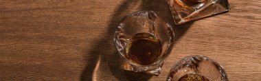 Top view of brandy in glasses and decanter on wooden table, panoramic shot clipart