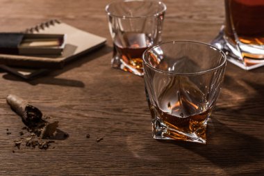 Selective focus of brandy in glasses with cigars, lighter and matches on wooden table clipart