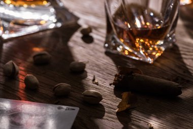 Kyiv, Ukrayna - 7 Kasım 2019: Tahta masa üzerinde iskambil, puro ve şam fıstığı bulunan brandy bardaklarının seçici odak noktası