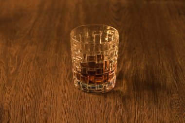 Textured glass of brandy on wooden table clipart