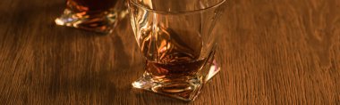 Two glasses of brandy on wooden table, panoramic shot clipart