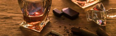 Glass of brandy with cigars, lighter and matches on wooden table, panoramic shot clipart